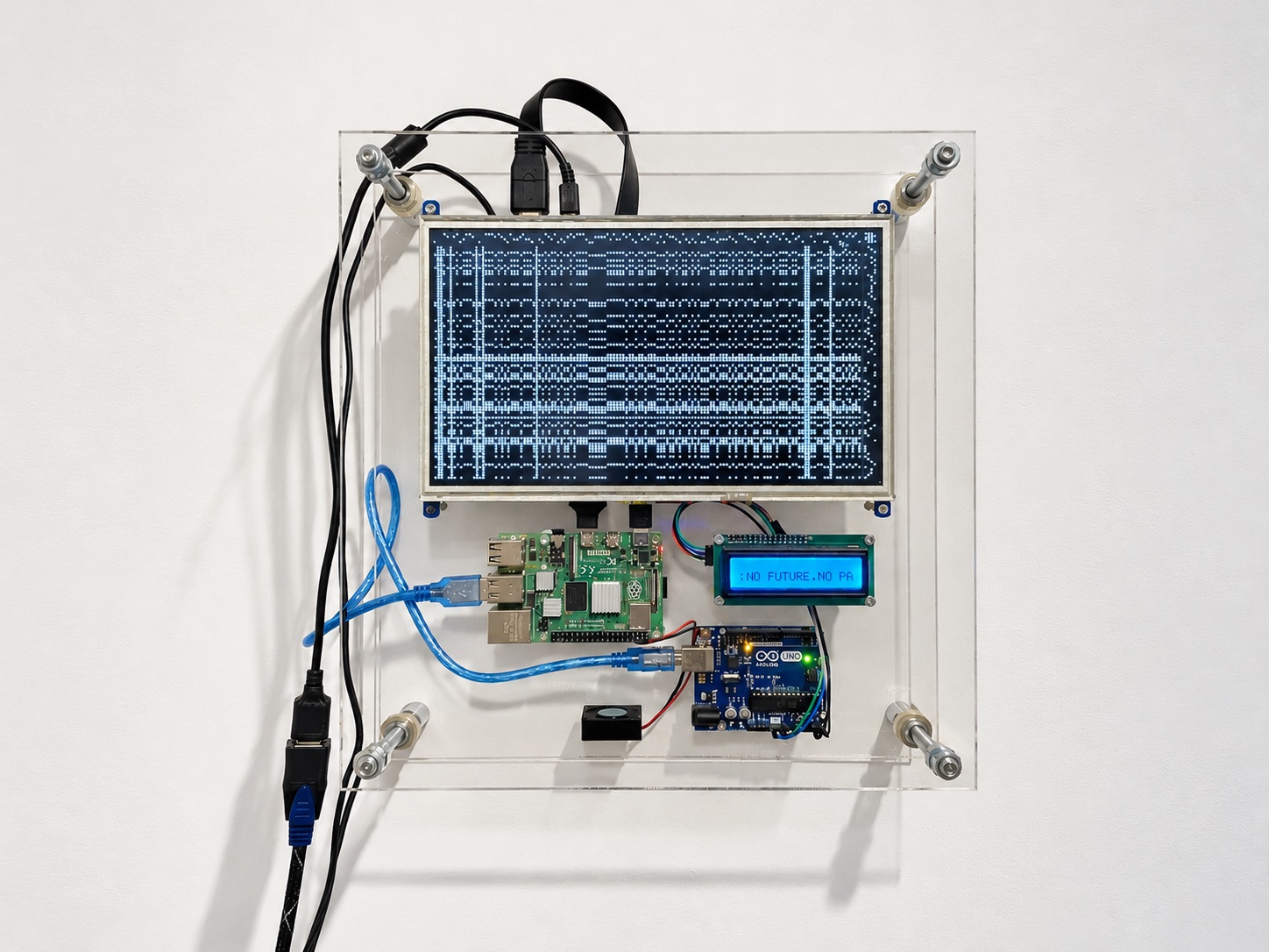 Front view on a white wall: a clear acrylic case holding a 10.1-inch LCD with a dotted weaving draft, a Raspberry Pi, an Arduino Uno, a small fan and a blue character LCD reading “NO FUTURE.NO PA”, with cables hanging down the left side