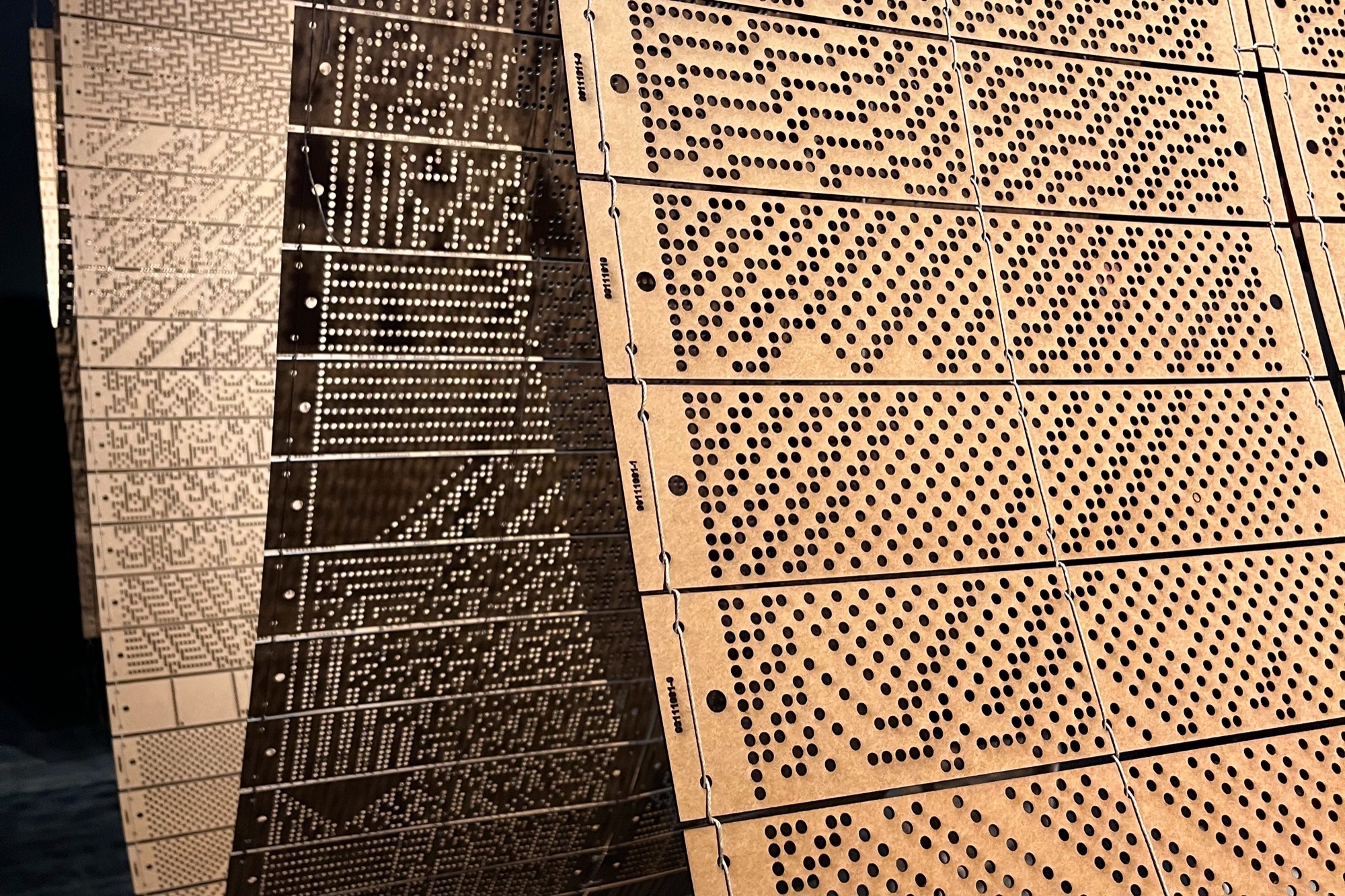 Close-up of perforated panels with varied hole patterns forming a curved surface